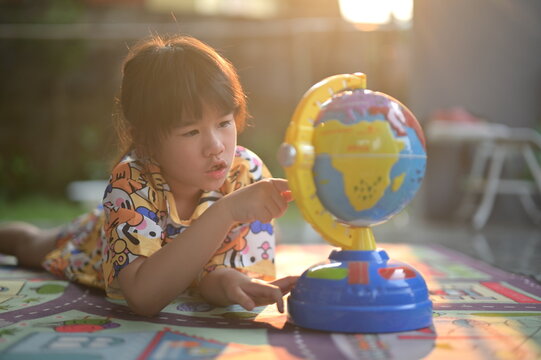 A young child explores a colorful globe, engaging with geography in a playful setting, highlighting curiosity and learning.