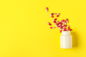 Jar with pink hard capsules on yellow background