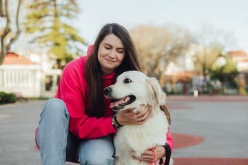 Young woman trains golden retriever puppy in the park in sunny weather. Happy dogs concept.