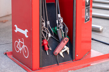 Close-up of bike repair station tools including wrenches and screwdrivers on red urban fixture