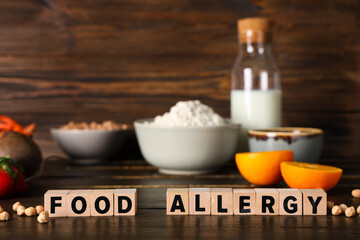 Text FOOD ALLERGY and different products on wooden table, closeup