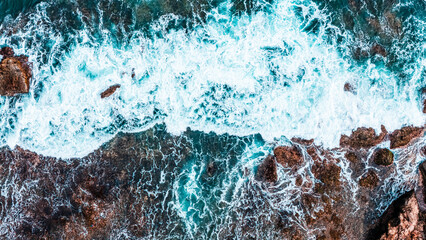 Aerial view of ocean waves crashing on rocky cliff in summer stunning seascape nature background.