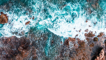 Seaside cliff with crashing waves, aerial drone photo of a sunny summer coastline.