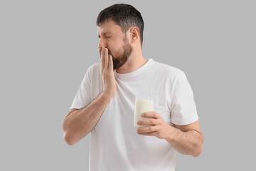 Sick young man with glass of milk on light background. Food Allergy Awareness Month