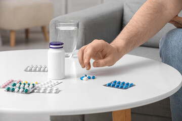 Male hand with different pills on table at home, closeup