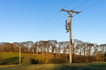 Wooden Electricity Utility Pole with Overhead Power Lines and Transformers in a Field Against a...