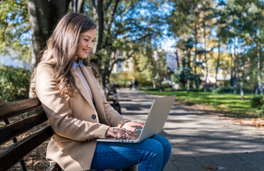 Successful businesswoman, office worker in corporate business, sitting on park bench working on laptop computer. Dedicated independent strong CEO female end of working time, finishing work outside.