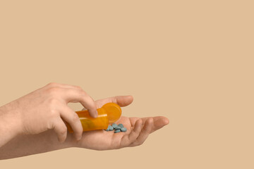 Male hands with pills on beige background, closeup