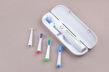 Modern electric ultrasonic toothbrush with rechargeable battery on a gray surface.
