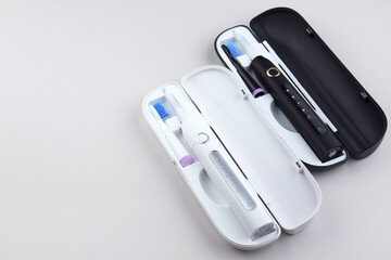 Modern electric ultrasonic toothbrush with rechargeable battery on a gray surface.