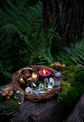 witch cauldron, burning candle and crystals in forest, dark natural background. occult ceremony,...