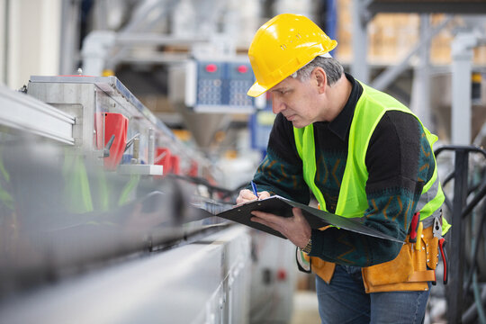 Senior worker in the factory operating machines - Powered by Adobe