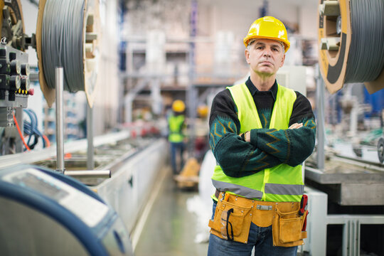 Senior worker in the factory operating machines and taking notes