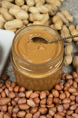Peanut butter in a jar among scattered peanuts