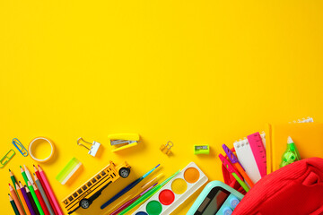 Back to school supplies flat lay: stationery and art items on yellow background