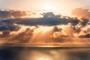 cloud in a form of flying sauser with light and shadows in amazing sunrise or sunset sky above water in beautisul seascape