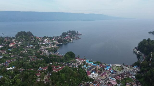Beautiful 4K aerial footage of Parapat Harbor at Lake Toba, North Sumatra, Indonesia. Captures the peaceful morning atmosphere with calm lake water, boats, and scenic hills