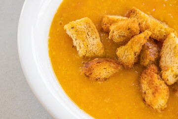 creamy tomato and zucchini soup served in a white bowl, topped with golden homemade croutons