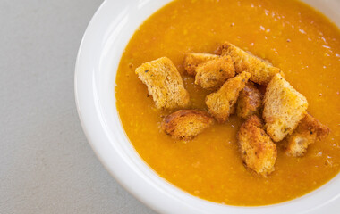 creamy tomato and zucchini soup served in a white bowl, topped with golden homemade croutons