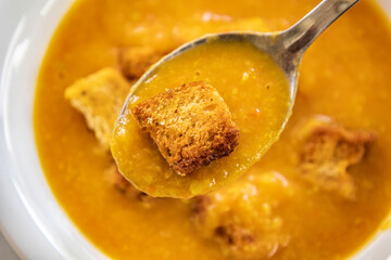 creamy tomato and zucchini soup served in a white bowl, topped with golden homemade croutons