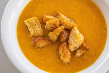 creamy tomato and zucchini soup served in a white bowl, topped with golden homemade croutons