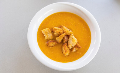 creamy tomato and zucchini soup served in a white bowl, topped with golden homemade croutons