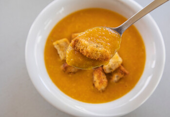 creamy tomato and zucchini soup served in a white bowl, topped with golden homemade croutons