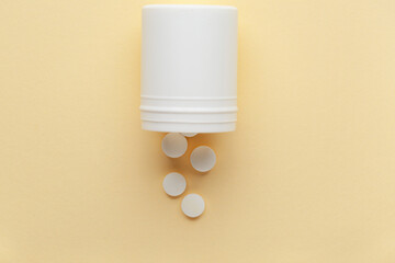 Jar with white pills on yellow background
