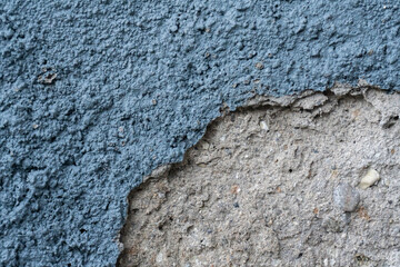 exture background of an old, weathered wall with cracked and peeling blue paint revealing the rough concrete surface underneath.