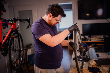 Man Working on Bicycle Wheel in Home Workshop Studio