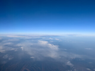 Fototapeta premium View from the porthole to the blue horizon and the earth under the clouds