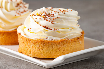 Lemon tartlets with whipped cream, sprinkles and chocolate chips on white background