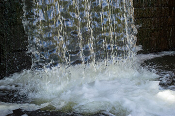 Water flows gracefully over rocks, creating a serene atmosphere with splashes and bubbles in a...