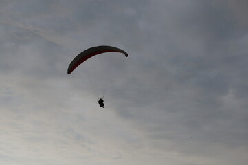 A man flying on a paraglider or gliding parachute. Silhouette of a flying man against the sky, view from below