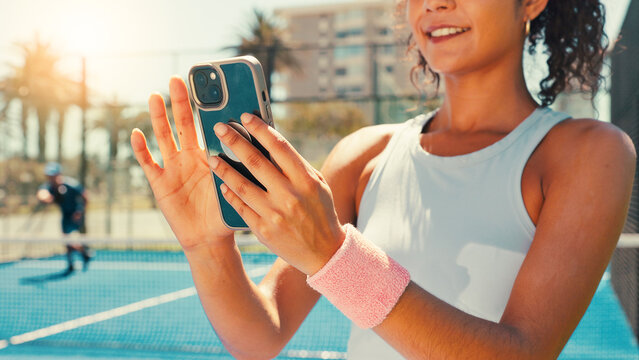 Tennis, hands and woman on court with phone, social media or scroll on training app for exercise tips. Athlete, smile or mobile on sports ground for blog update, fitness research or club registration