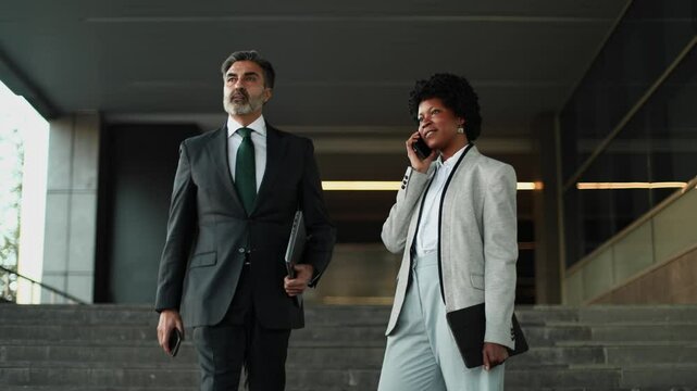 Businesswoman walking and talking on phone outside office