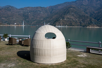 A dome sofa invites relaxation in the lawn that overlooks a lake. Chairs and tables around create a comfortable area for socializing and enjoyment.