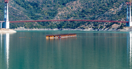 Floating huts are situated in the lake, providing unique accommodations. A bridge over it connects various areas and enhances the scenic view.
