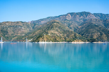A picturesque scene features a bridge, a boat, and tall mountains with a lake below. This landscape invites exploration and appreciation of nature.