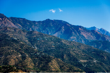 Green mountains are covered in a blue mist, creating a mystical atmosphere. Small villages on the slopes add charm to the natural landscape.