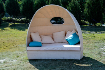 A dome sofa with white and blue cushions in the lawn offers a cozy spot for relaxation. Sunlight shining through creates a warm and inviting atmosphere.