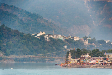 The town of Rishikesh is situated on both sides of the river, featuring a bridge that connects the two areas. The lively atmosphere attracts visitors.