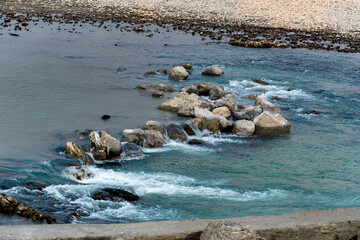Rocks in the river Ganges create a beautiful scene as water flows between them, leaving white foam...