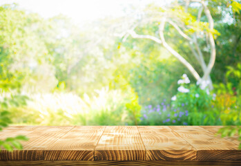 Real photographs of wood table top on blur bokeh greenery tree and flower from garden background.