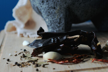 Guajillo peppers, garlic and other spices sitting in front of a molcajete before 