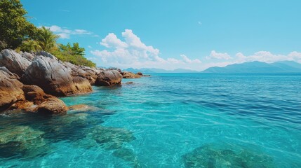 Fototapeta premium Crystal Clear Waters and Rocky Coastline Under a Bright Blue Sky in a Serene Tropical Landscape