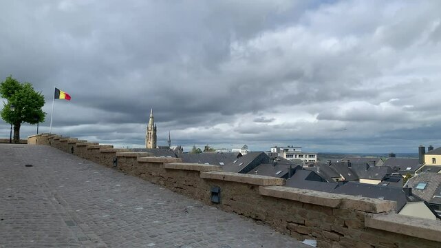 Panoramic, scenic skyline view of Arlon city buildings rooftops and Saint Martin church. Belgian flag is waving on top of Saint Donat church hill.  Arlon, Belgium