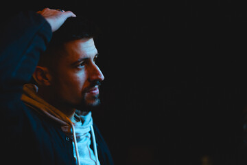 Man with hand on head engages in thoughtful reflection during night setting in urban environment