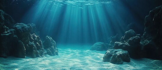 Obraz premium Underwater sunbeams, sandy ocean floor, rocks, background