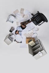 Naklejka premium Photo upside down. Young businesswoman lying on office floor talking on phone surrounded by scattered documents and messy furniture. Concept of office lifestyle, human emotions, business